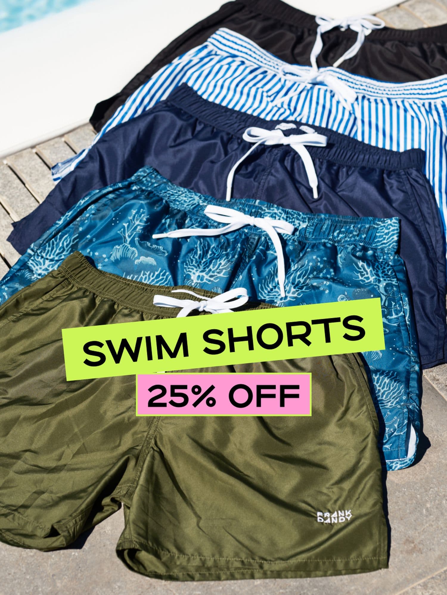 Four pairs of swim shorts in different colors and patterns displayed near a pool. A sign reads "Swim Shorts 25% Off."