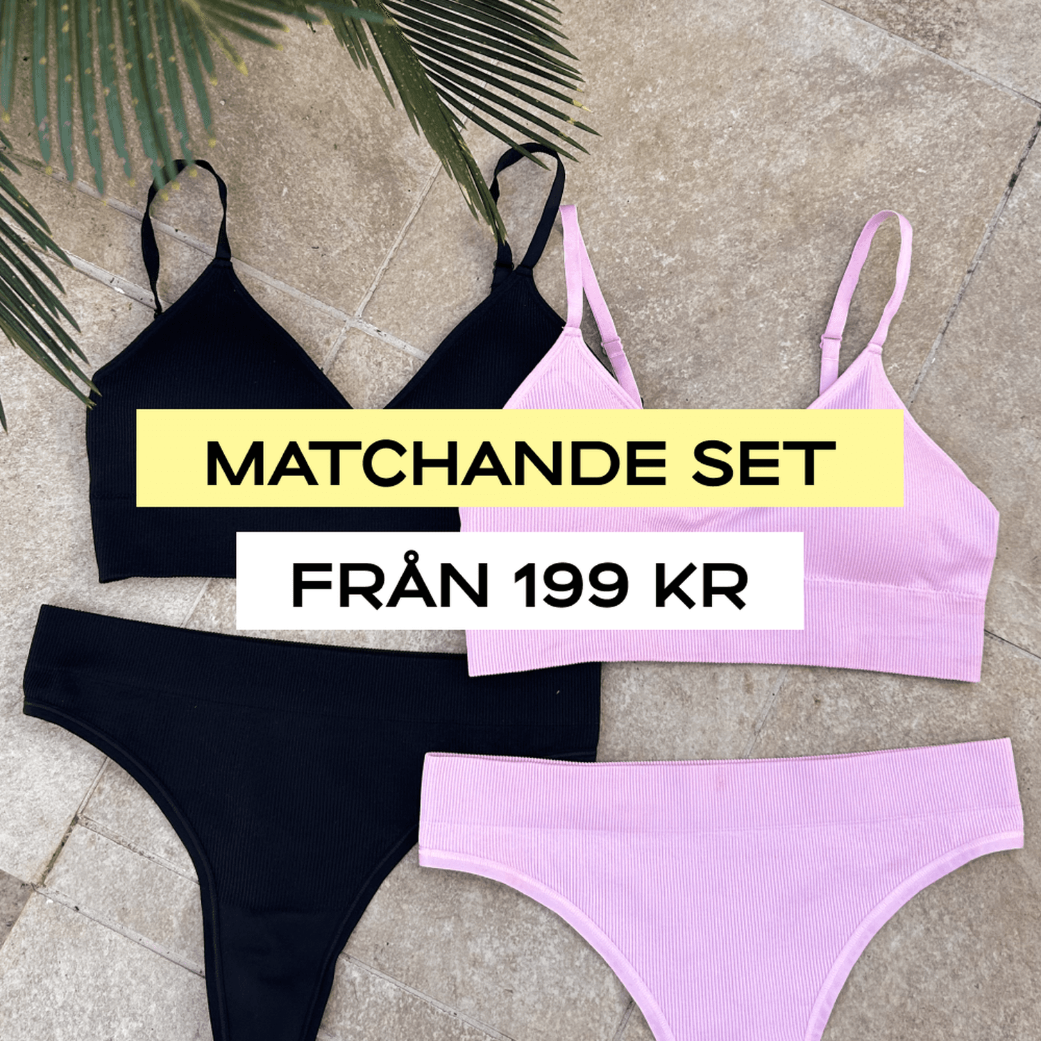 Two matching bra and panty sets in black and pink are laid out on a tiled surface with palm leaves in the corner.